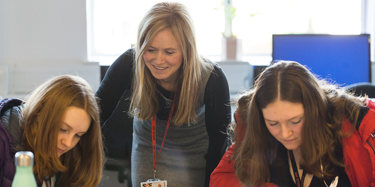A teacher supporting two students with their work