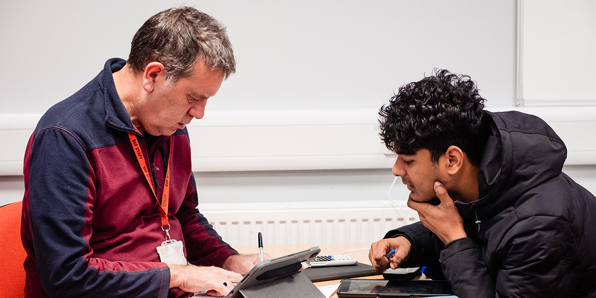 A teacher supporting a student in a maths lesson